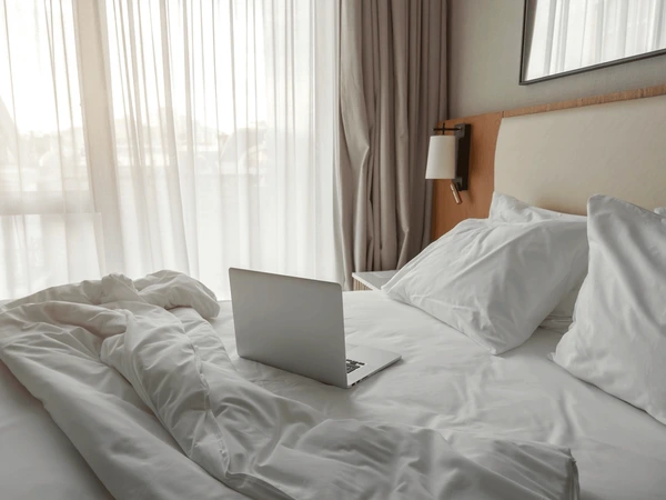 Open notebook beside a folded blanket on a bed